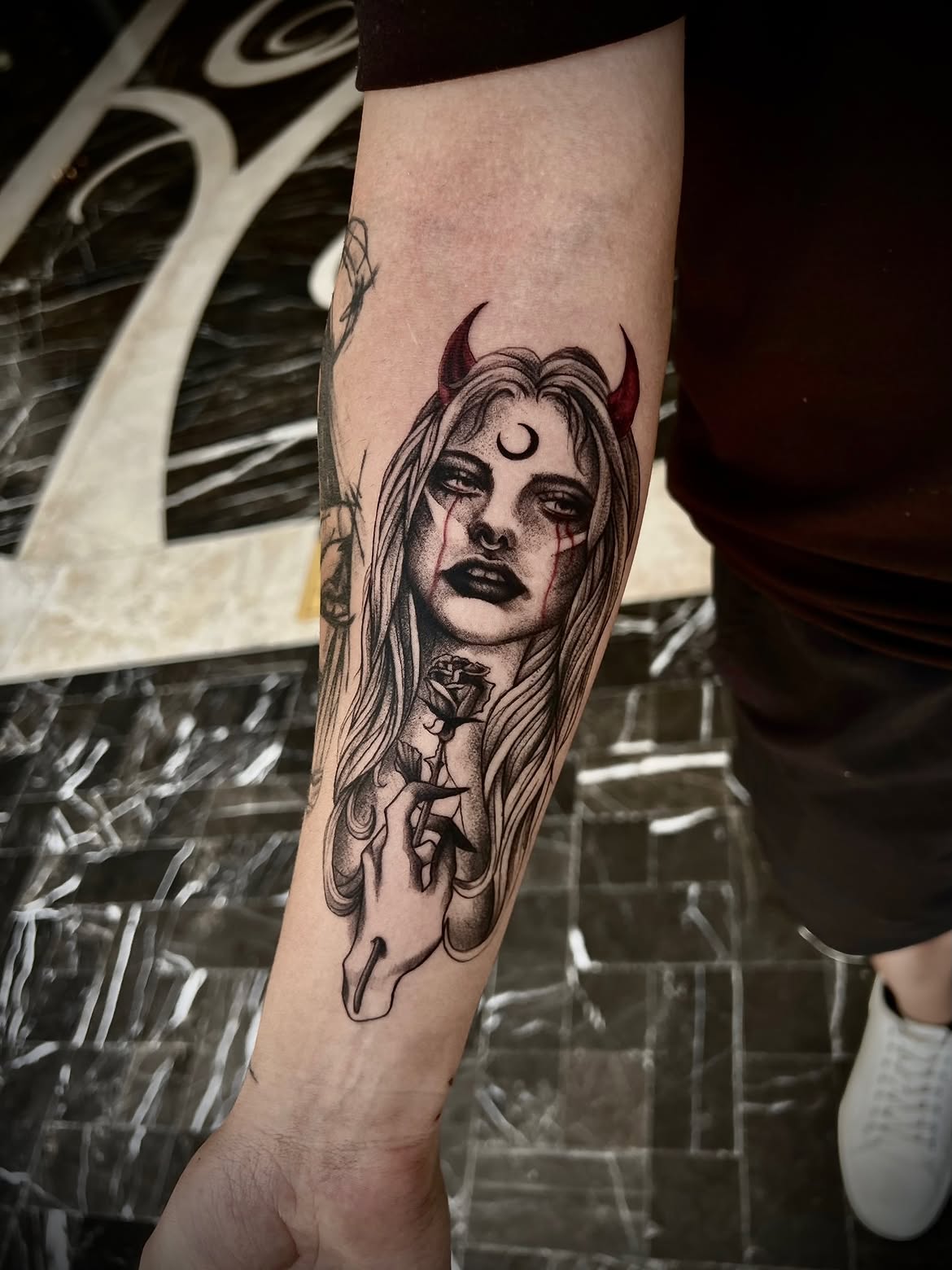 Dark illustrative tattoo of a horned figure with a rose